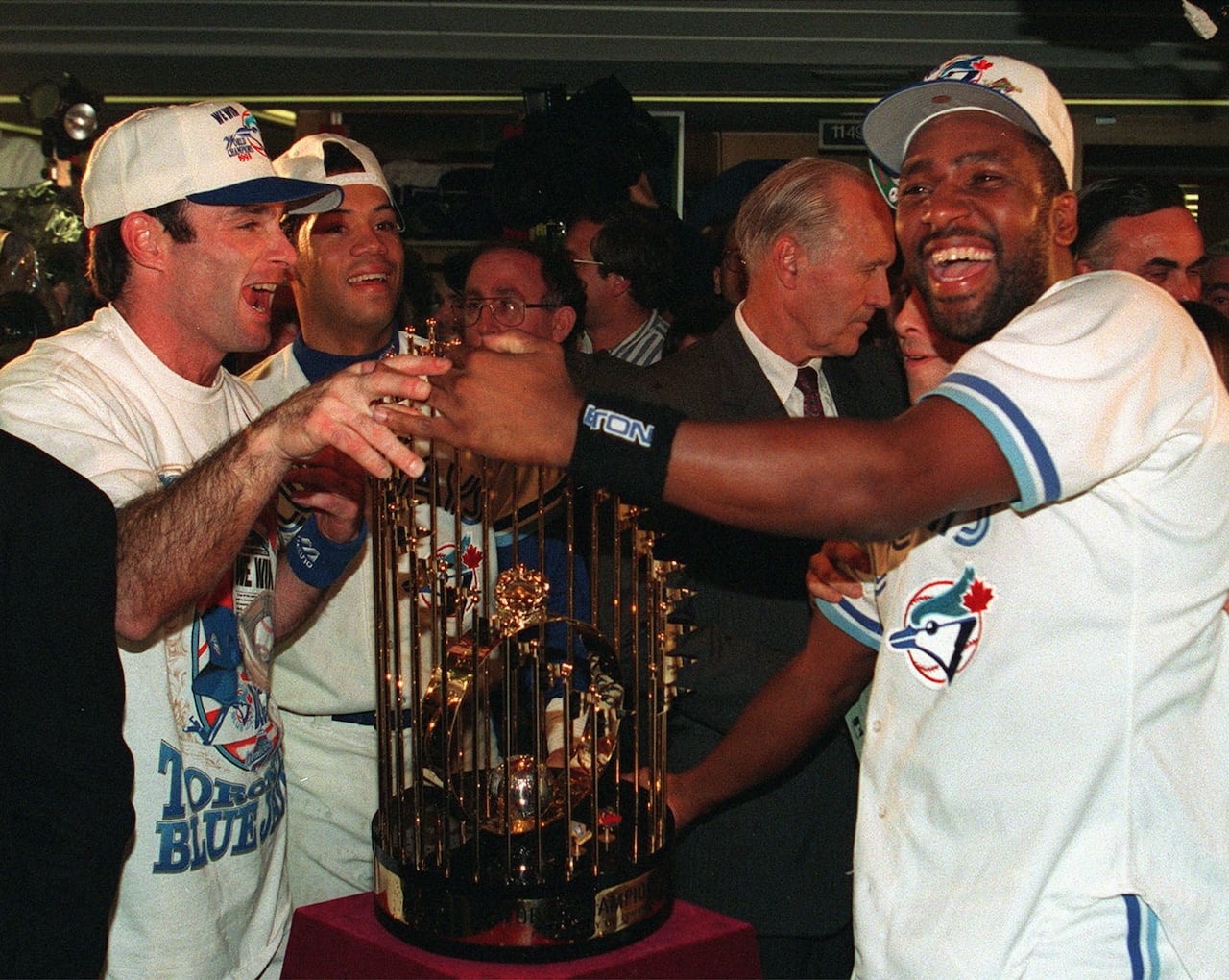 Several baseball players standing alongside a trophy