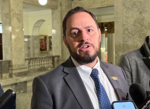 A man in a suit is seen being interviewed by reporters.