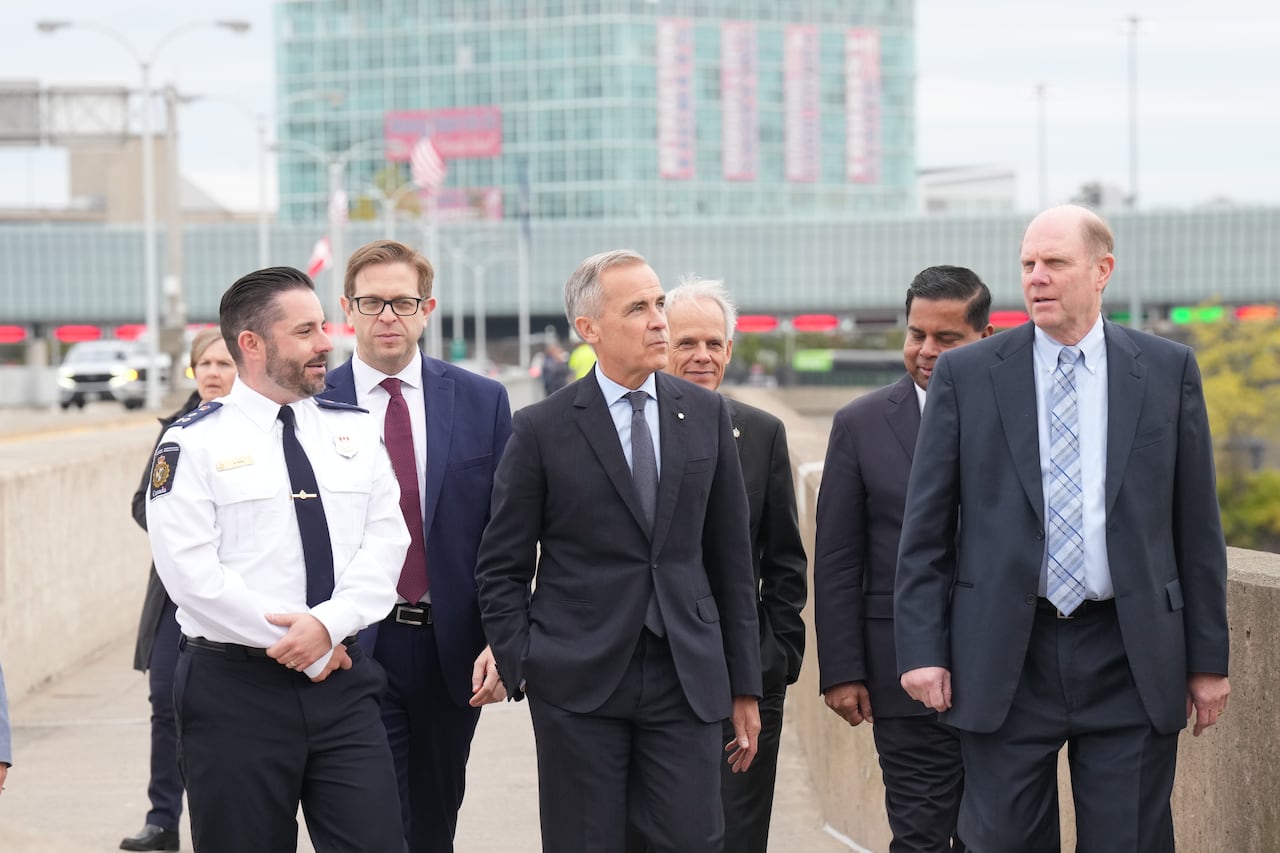 Un grupo de funcionarios gubernamentales y trabajadores fronterizos cruzan el cruce fronterizo del Puente Arcoíris.