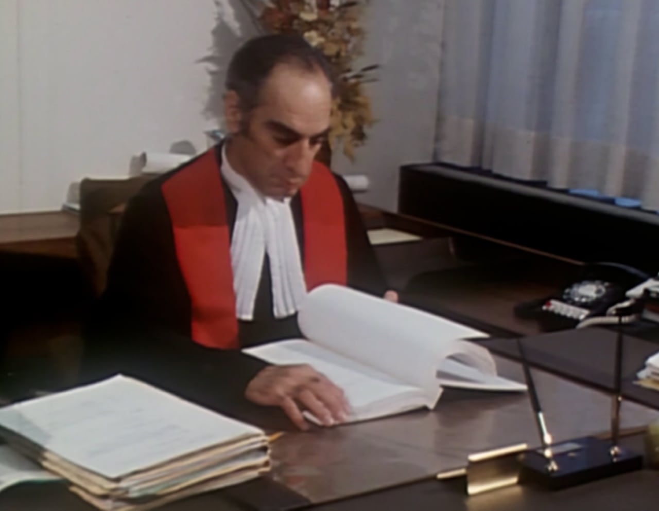 Man in court judge wear sits by a table reading a book