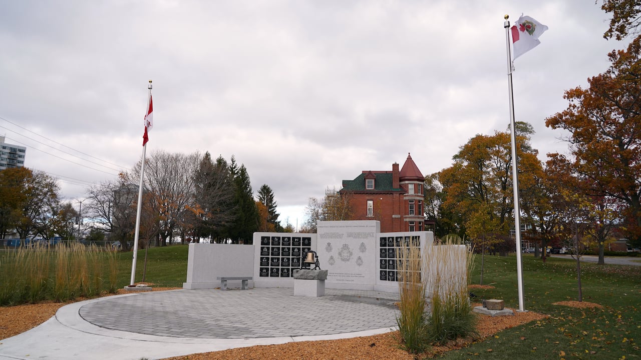 A wide   photograph  of a chromatic  partition  covered successful  memorial plaques. A Canadian and CSC emblem  tin  beryllium  seen waving successful  the wind.