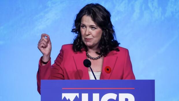 Danielle Smith, leader of Alberta's UCP speaks from a podium. Danielle Smith, leader of Alberta's UCP, speaks into a microphone at a podium.