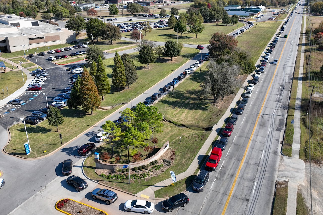 An aerial view shows a long line of cars lining up.
