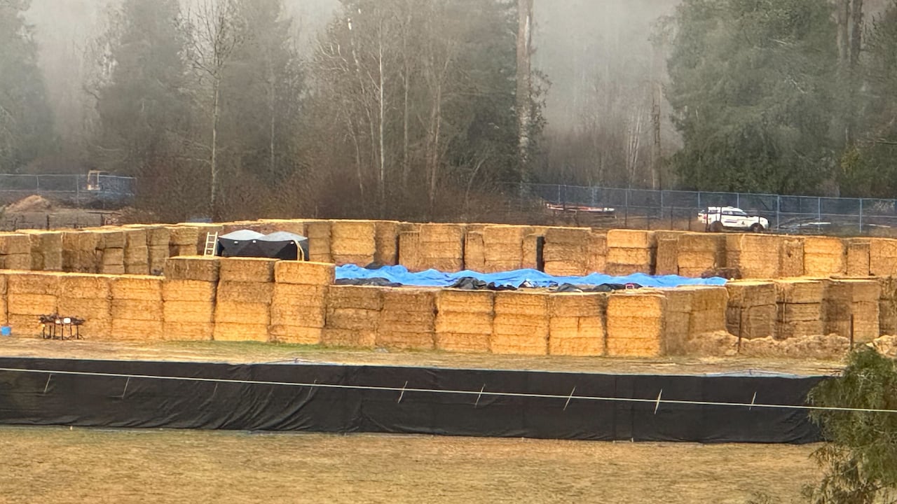 An aerial changeable  of bluish  tarps wrong  a straw bale enclosure.