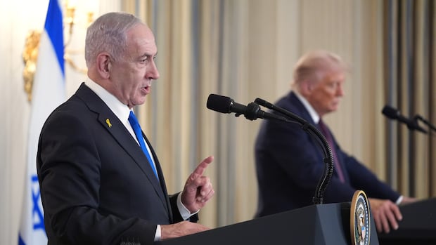 medium shot of man standing at podium with another man at a podium in the background