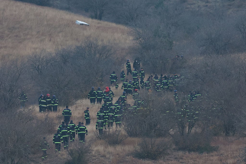 The rescue workers who are not the same are found on the grassy field.