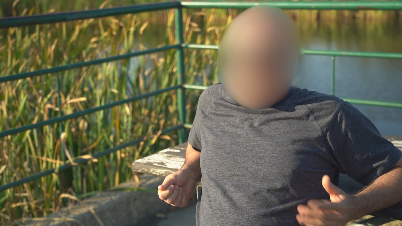 Un hombre borroso sentado frente a un banco del parque.