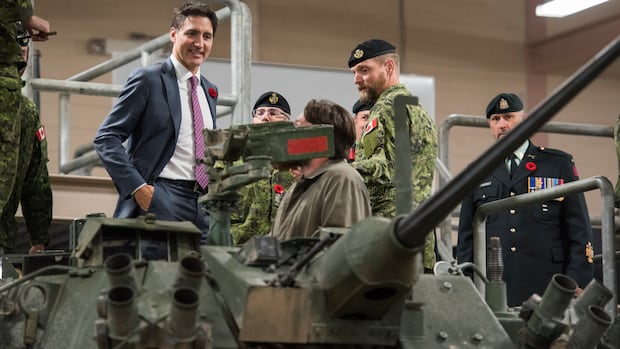 A man in a suit stands behind a tank