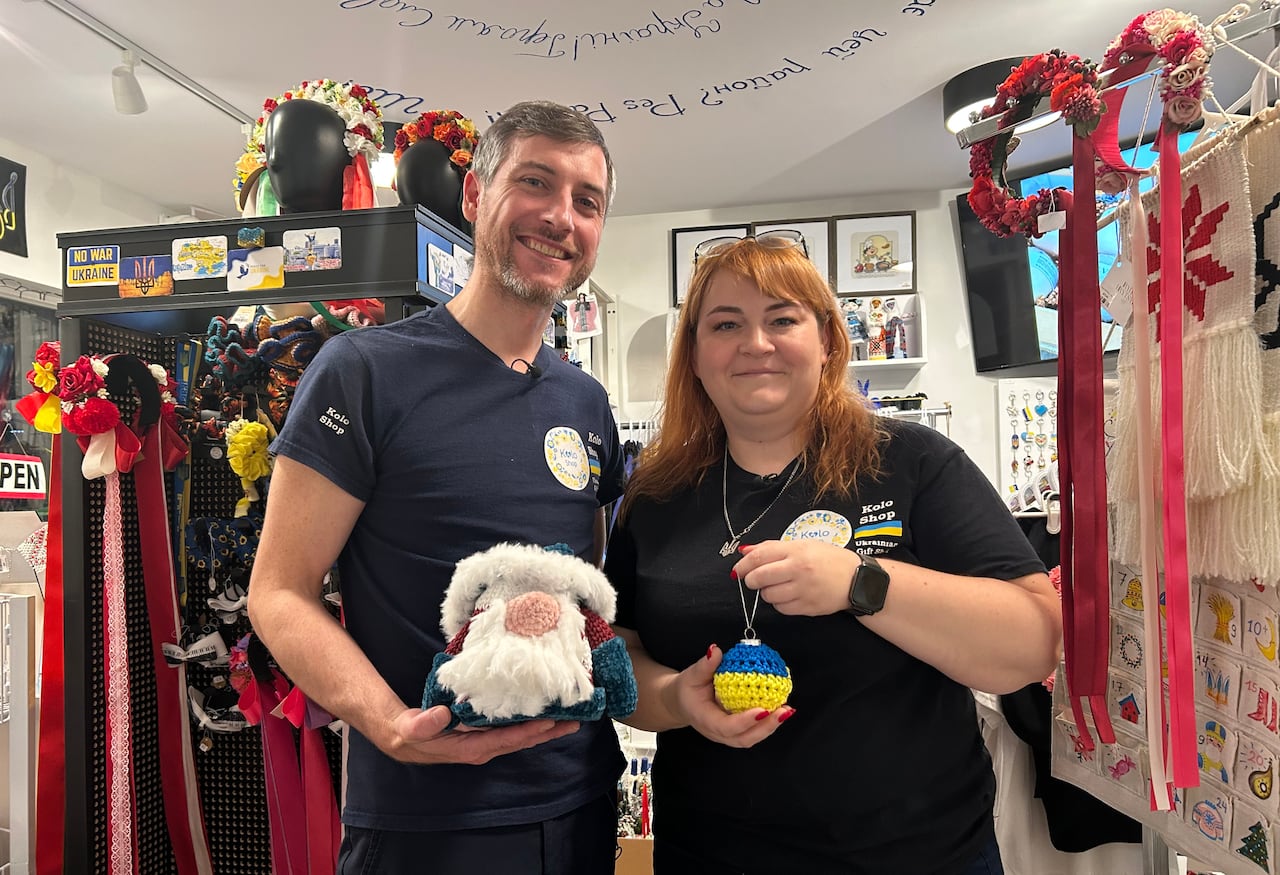 A man and woman stand beside each other inside a gift shop holding holiday decorations.