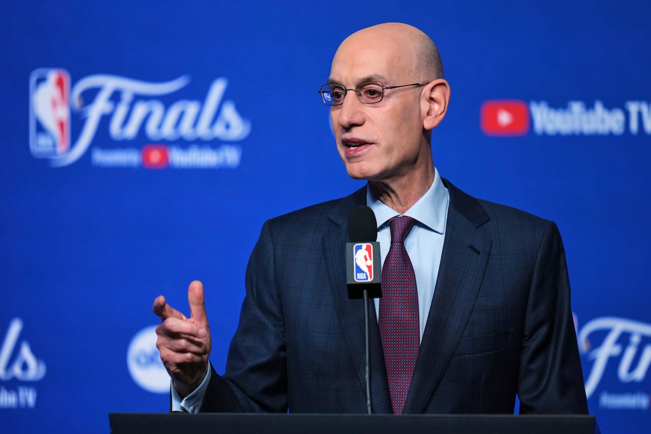 bald man in a blue suit gestures as he speaks