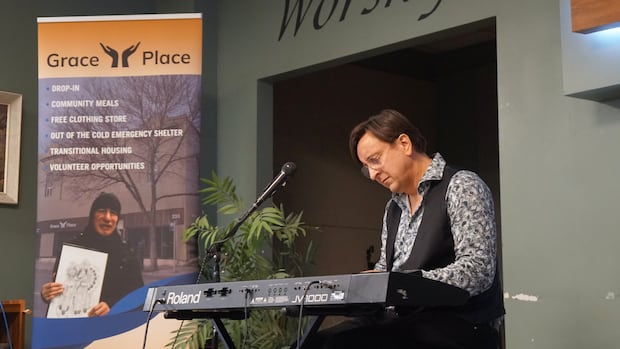 Mike Boguski, the keyboardist for Canadian rock band Blue Rodeo, is seen during a solo performance at Grace Place in Thunder Bay, Ont. A person is seen playing the keyboard on a small stage indoors.
