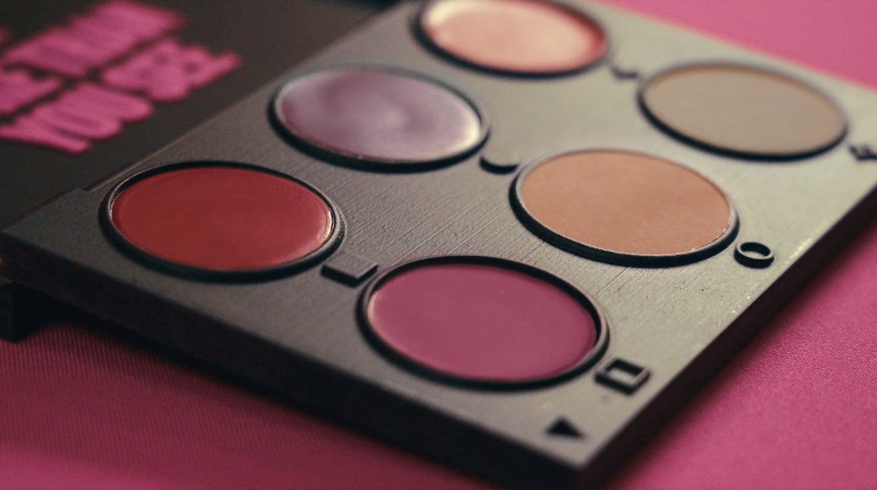 A makeup palette with six circles of products. Each product has a small symbol underneath it, like a square, circle or star.