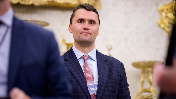 Man in blue suit stands in front of gold ornaments