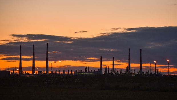 A view shows the Orenburg gas processing plant of Gazprom in the Orenburg Region, Russia in September 2023. The sun sets behind the silhouette of an oil refinery.