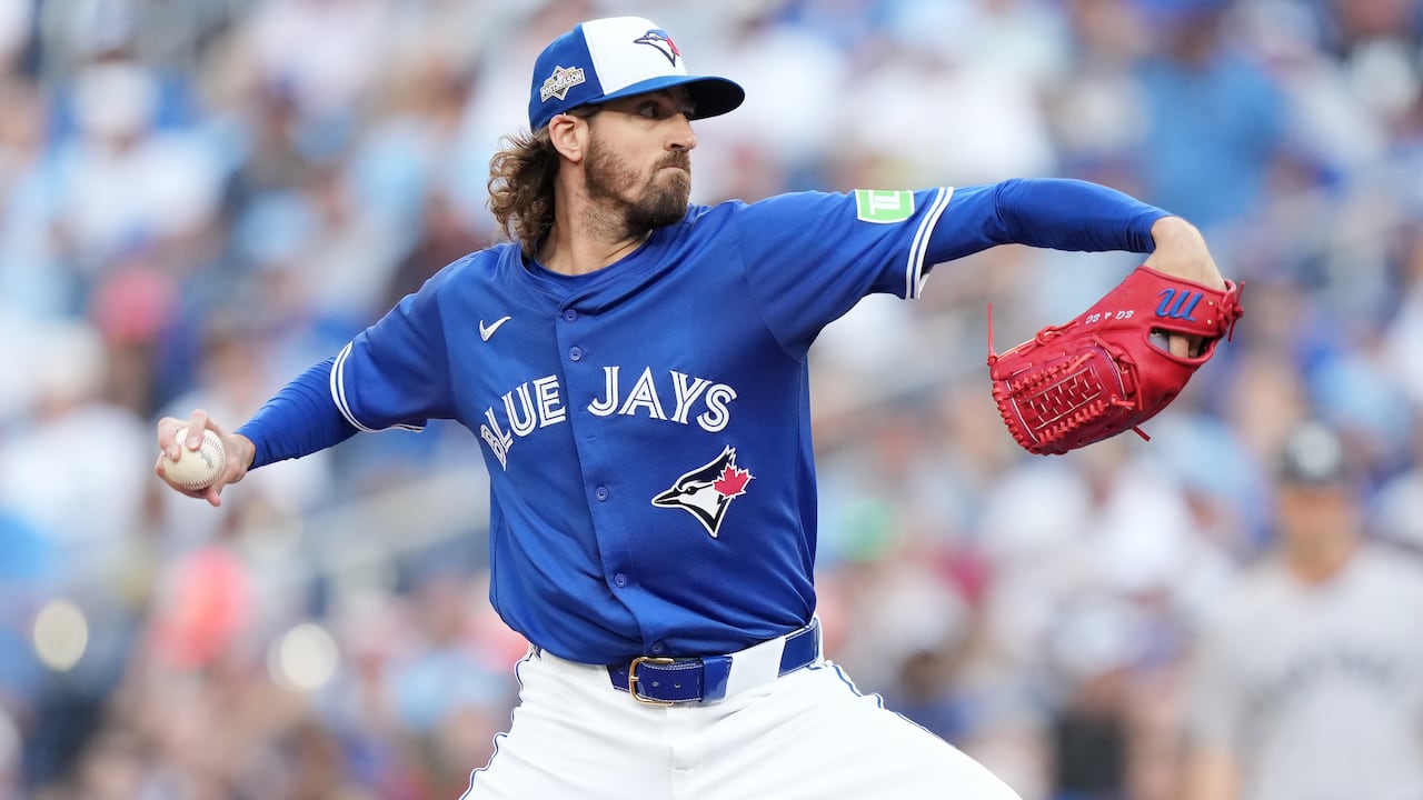 A male baseball pitcher winds up to throw the ball with his right hand.