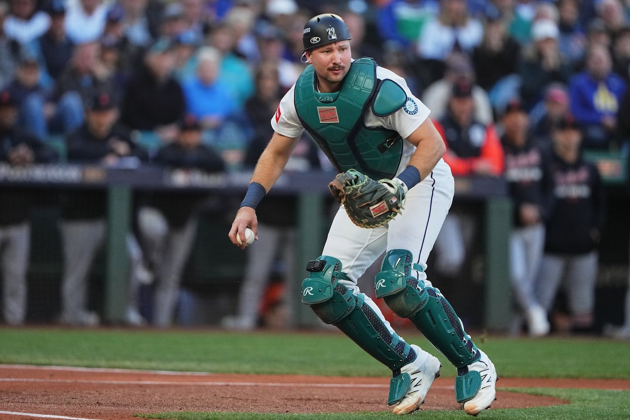 Cal Raleigh, Seattle Mariners catcher, in full gear, throws a ball on a baseball field in game play