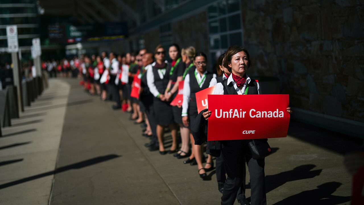 People in suits walk outside holding signs. 