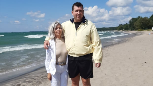 A woman and a man stand on a beach