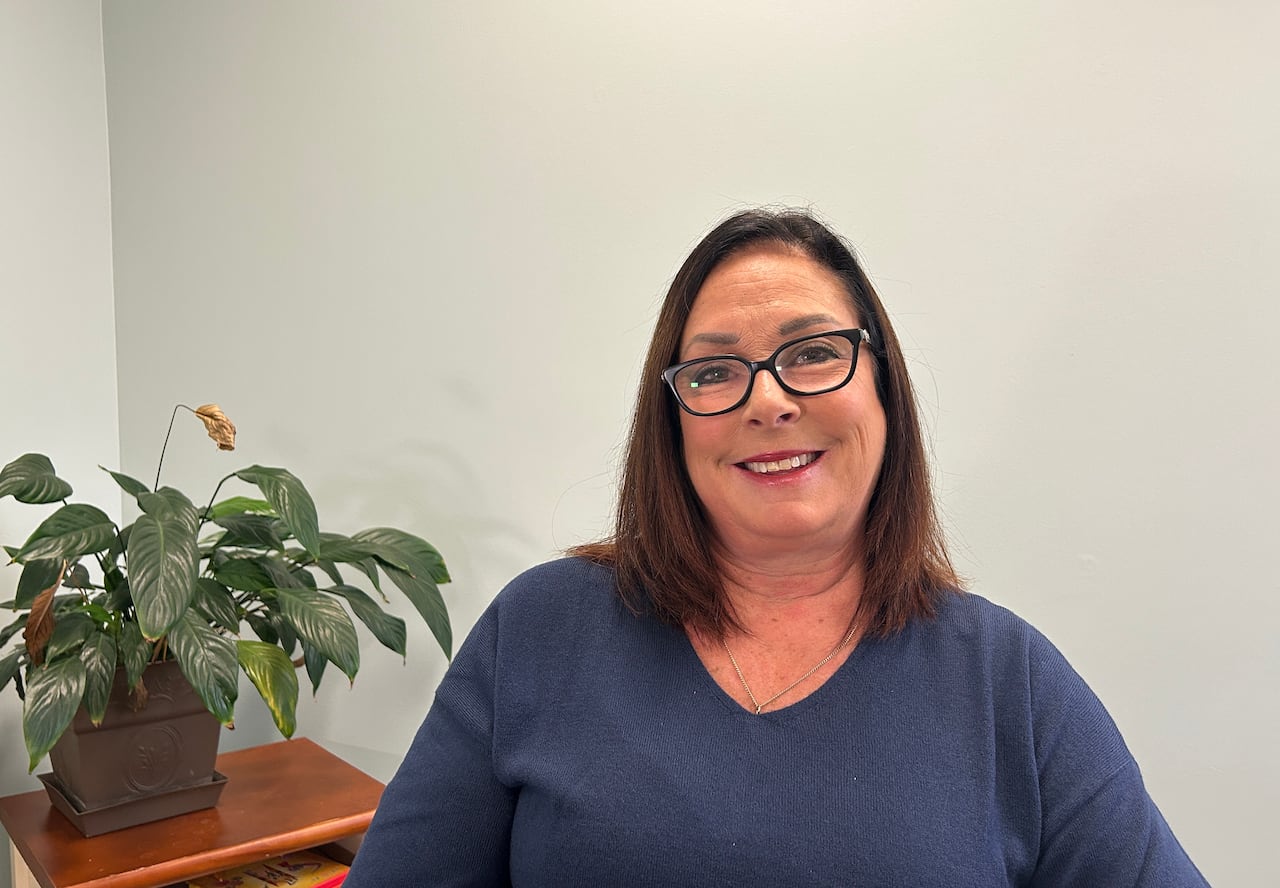 Woman wearing navy sweater and glasses smiles for a picture