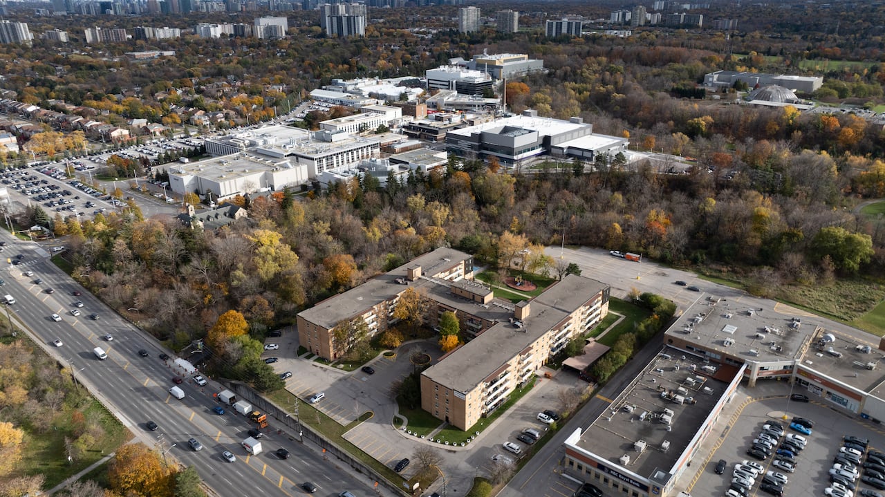 A aerial view of a low-rise apartment complex, with a much larger complex behind it. 