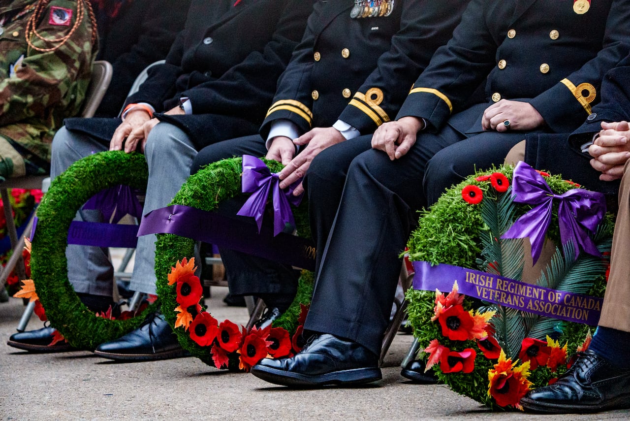 legs of uniformed officers with wreaths beside them