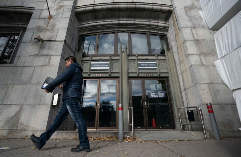 Un hombre pasa junto a un edificio en el que hay algo escrito.