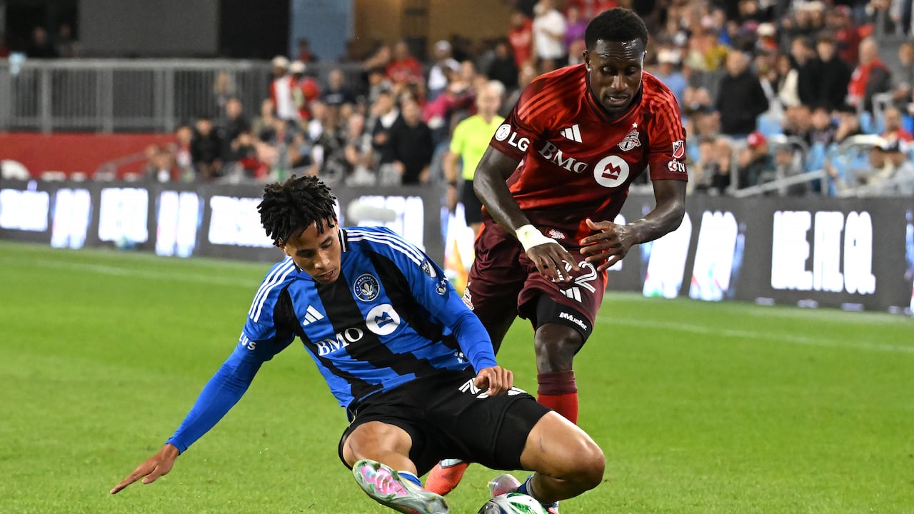 A men's soccer player tackles another during a match.