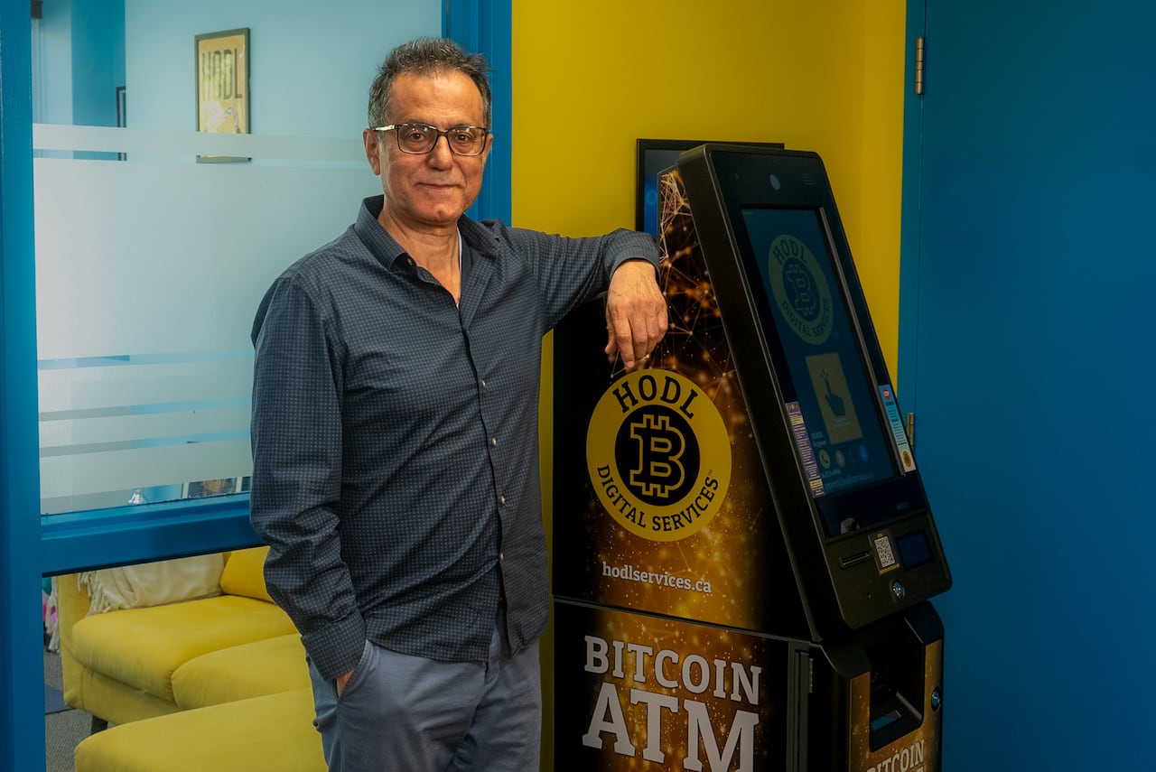 Man standing beside a cryptocurrency ATM.