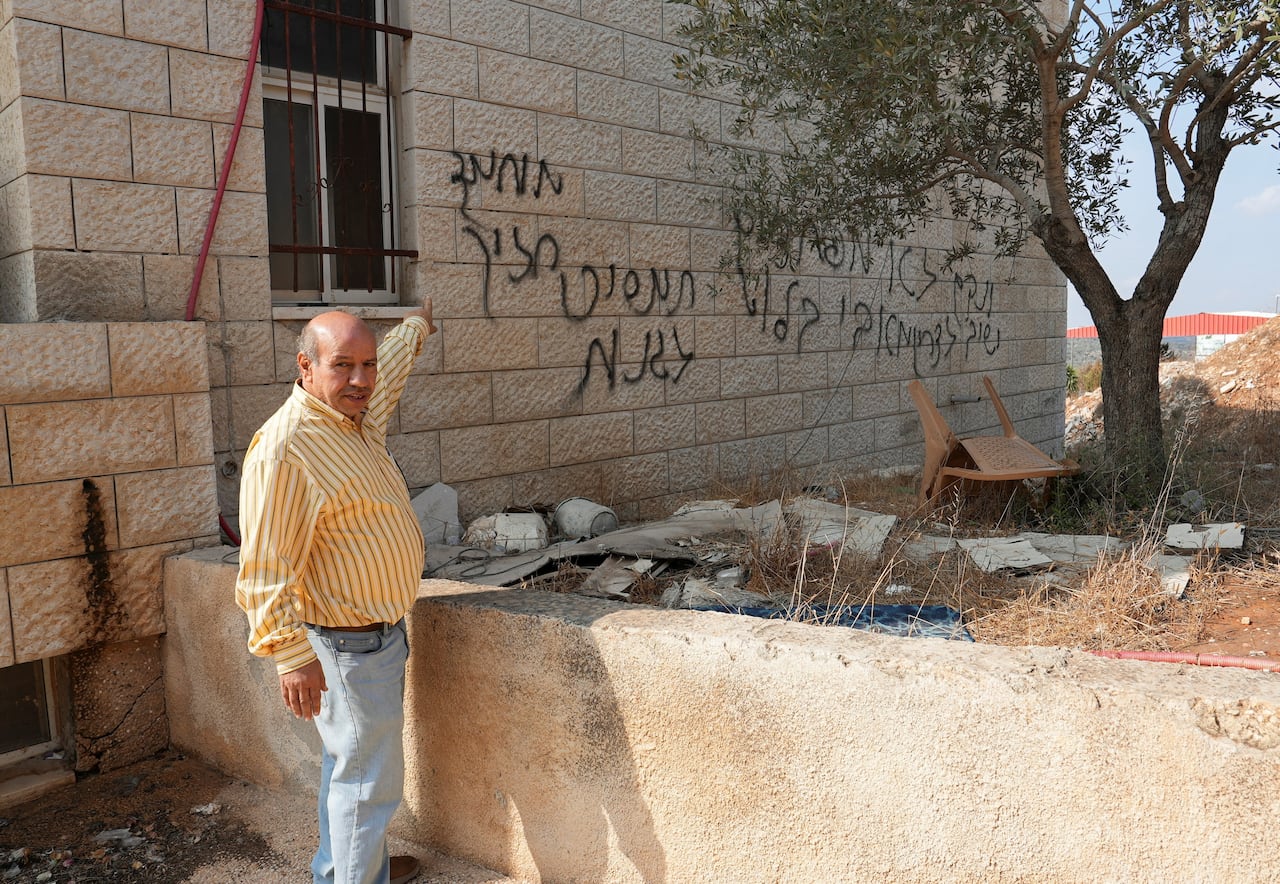 The man points to the graffiti on the building.