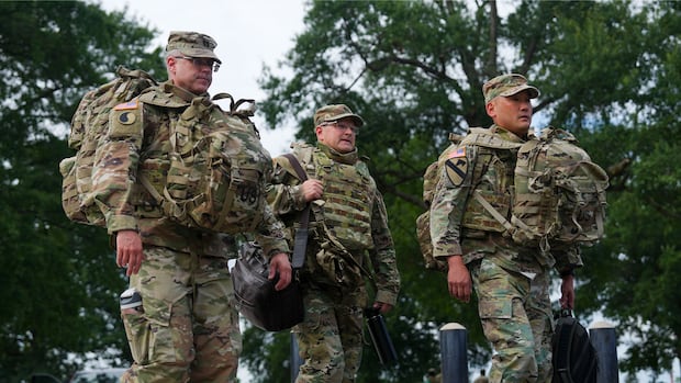 Three men in military fatigues walk. 