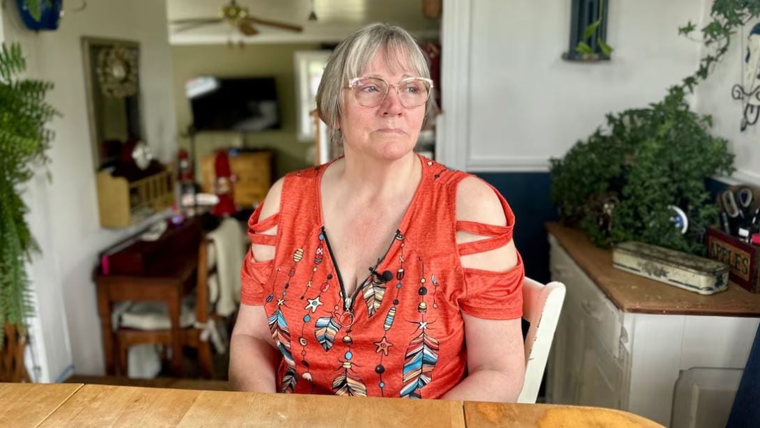 woman in orangey pink t-shirt seated at a wood table