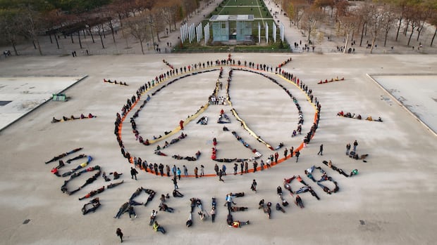 Environmentalist activists form a human chain representing the peace sign and the spelling out "100% renewable", on the side line of the COP21, United Nations Climate Change Conference near the Eiffel Tower in Paris on Dec. 6, 2015. The landmark Paris Agreement was signed days later. Environmentalist activists form a human chain representing the peace sign and the spelling out "100% renewable" near the Eiffel Tower