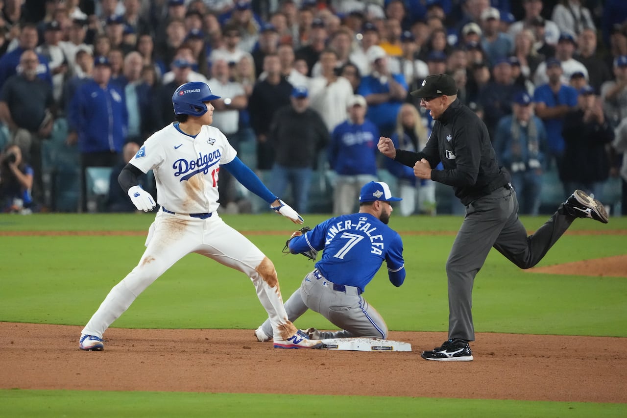 A baseball player trying to steal second base but it tagged out.