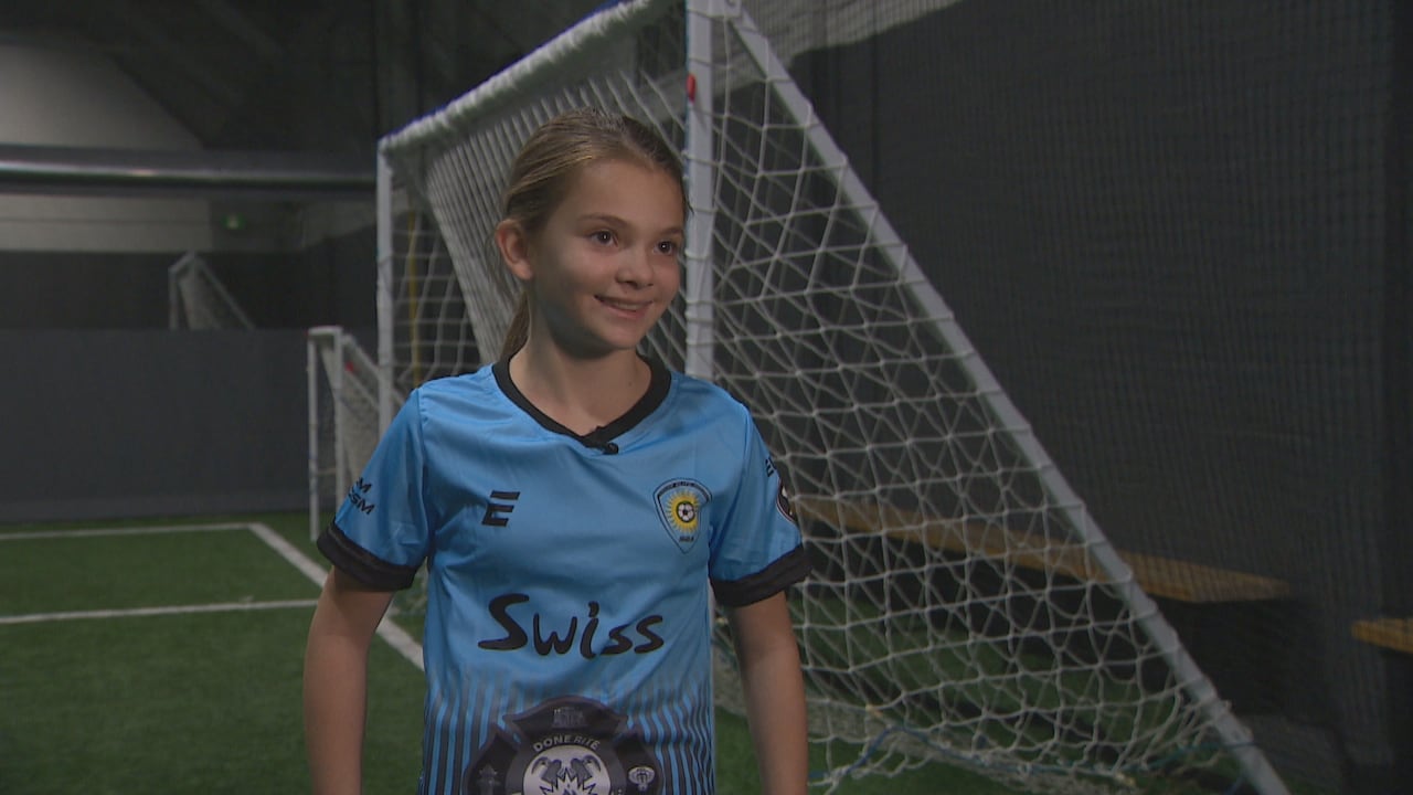 Smiling girl in soccer uniform in front of the net