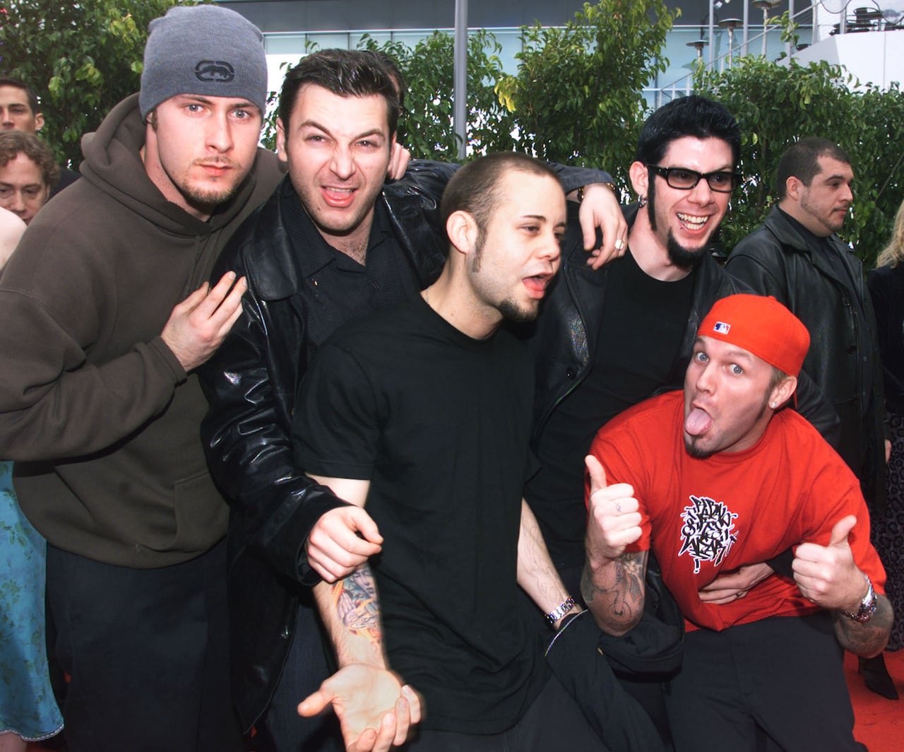 A group of five men pose for a photo on the red carpet at an awards ceremony. 