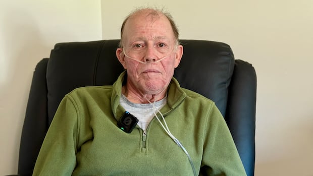 Guy Pollock says he was deathly afraid he'd catch something as an estimated 2,000 people wandered past the bed in the hallway of Royal University Hospital in Saskatoon. A man in a green sweater looks directly into the camera.