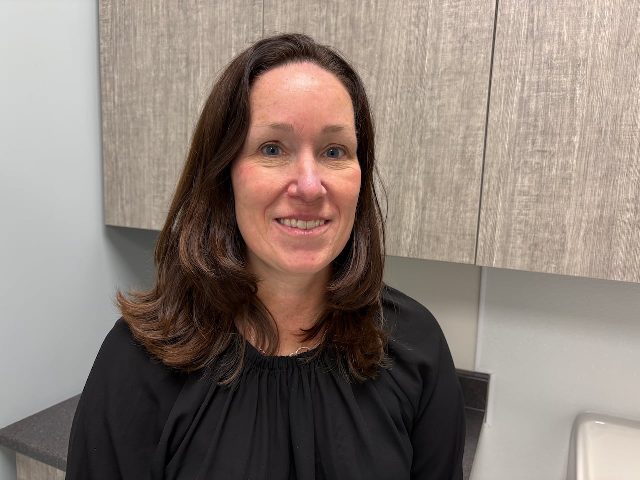 A woman stands in a clinic office. 