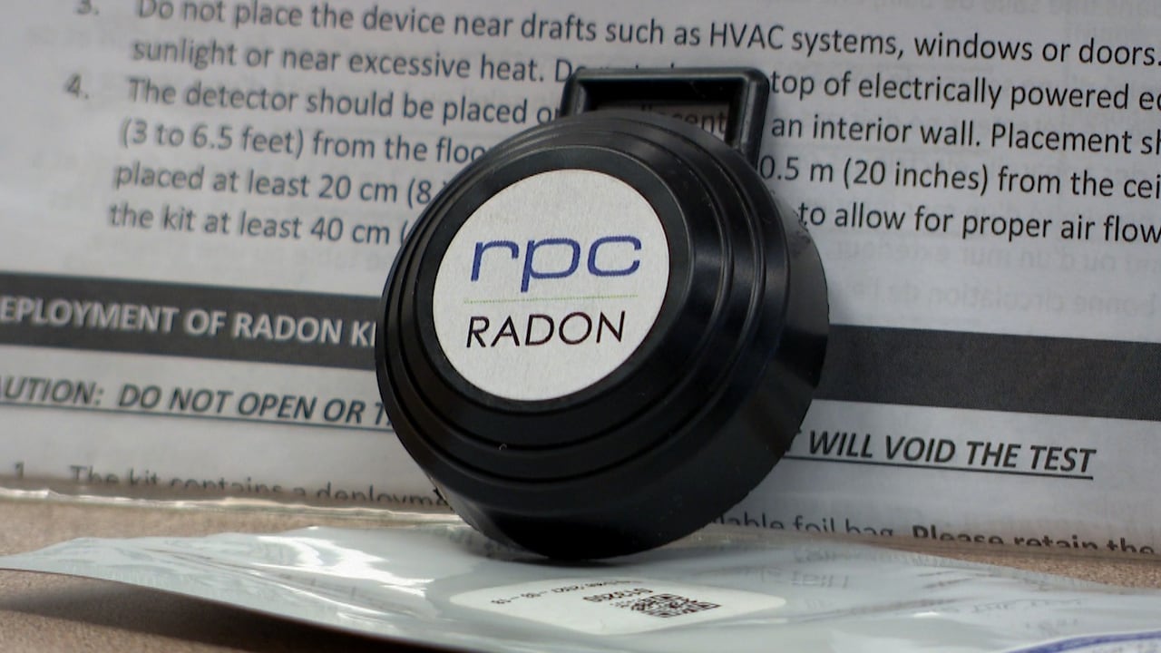 A small black, circular device that says RPC RADON on it. An instruction pamphlet is behind it. 