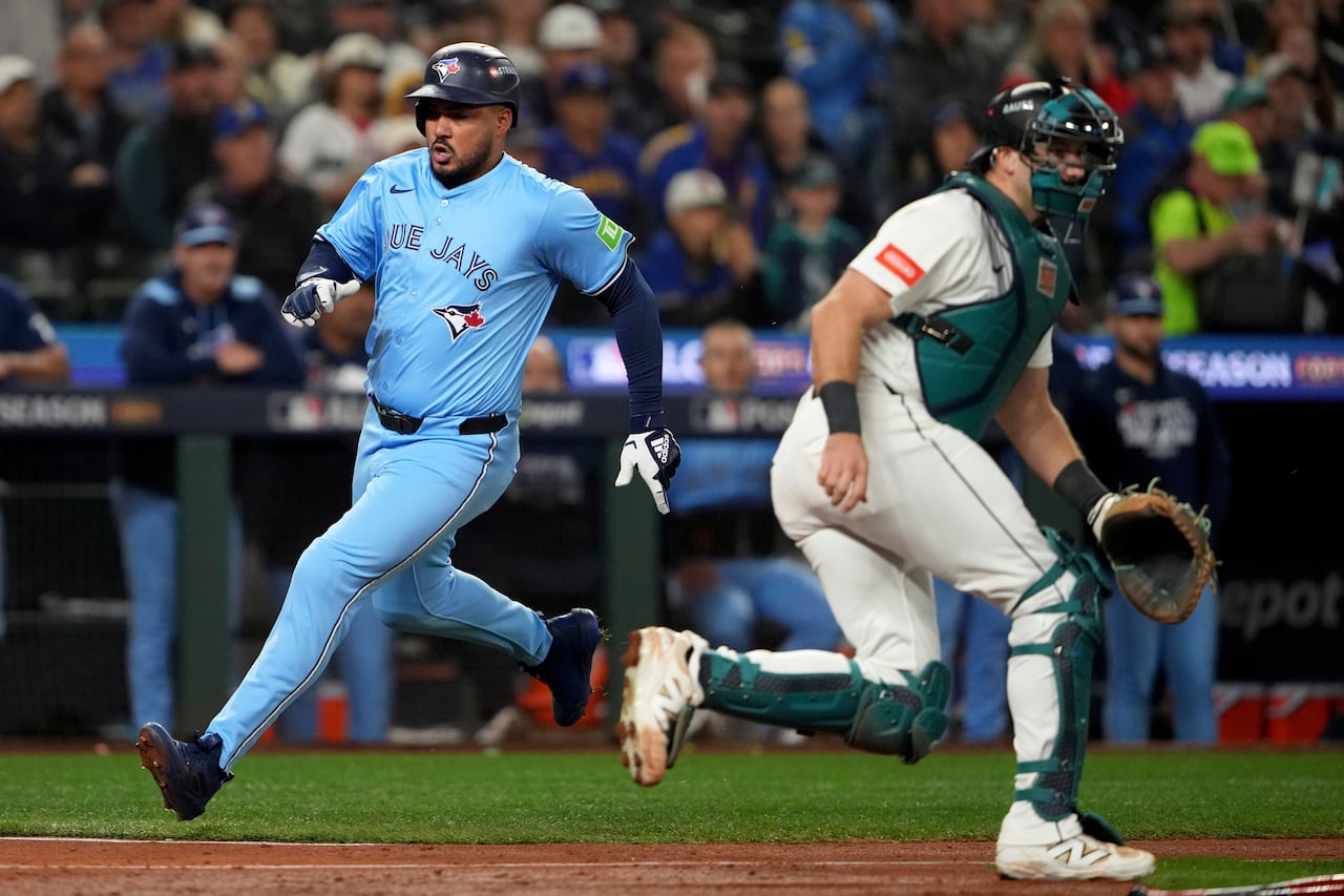 A baseball player crosses the plate, with the opposing team's catcher standing nearby