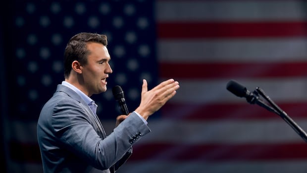 A man standing in profile in front on an American flag.
