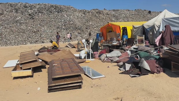 Encampment next to a tall landfill mound