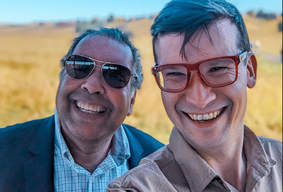 two smiling people with a yellow field as backdrop