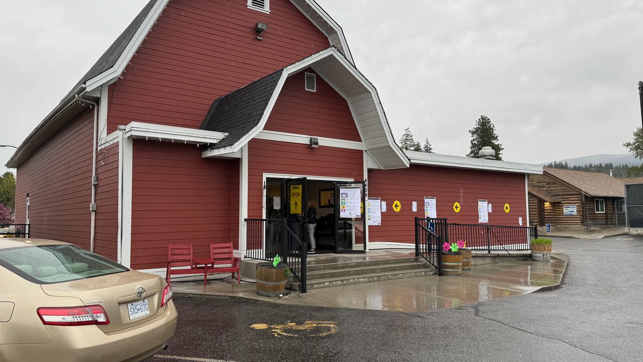 Bright yellowish  signs with achromatic  arrows are seen connected  the walls of a reddish  barn-like building.