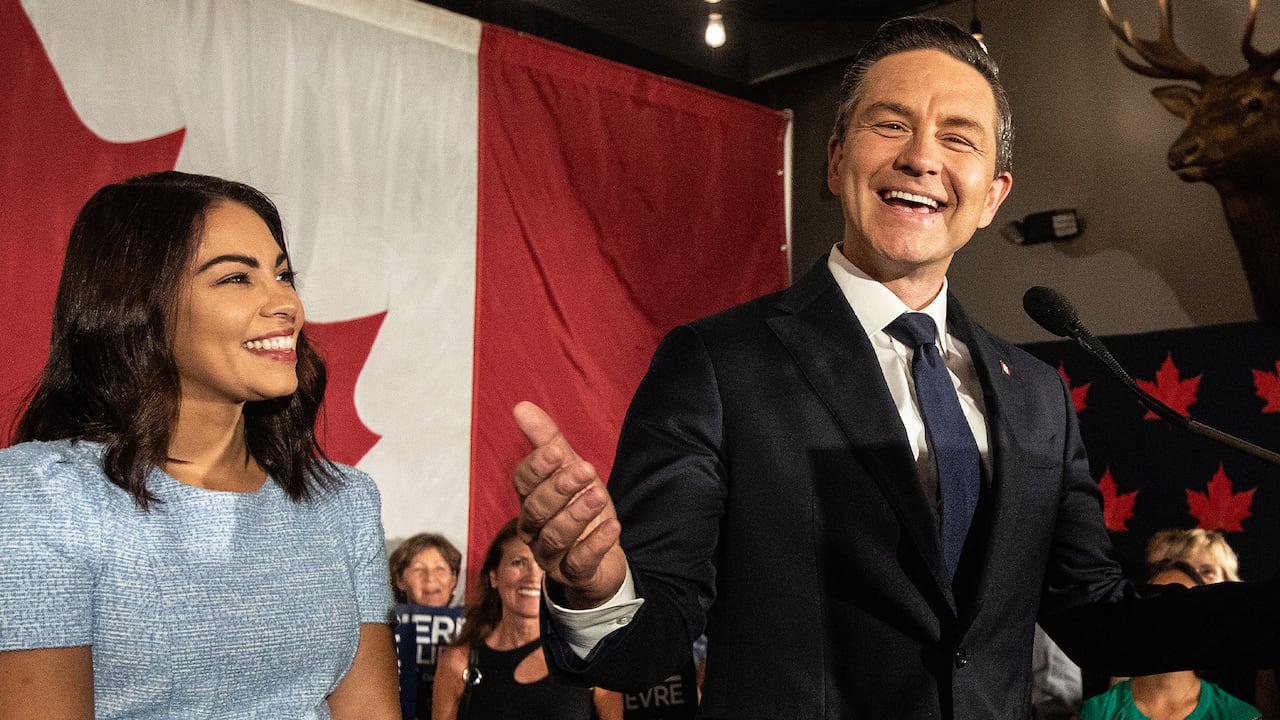 A man and a woman smile on a stage.