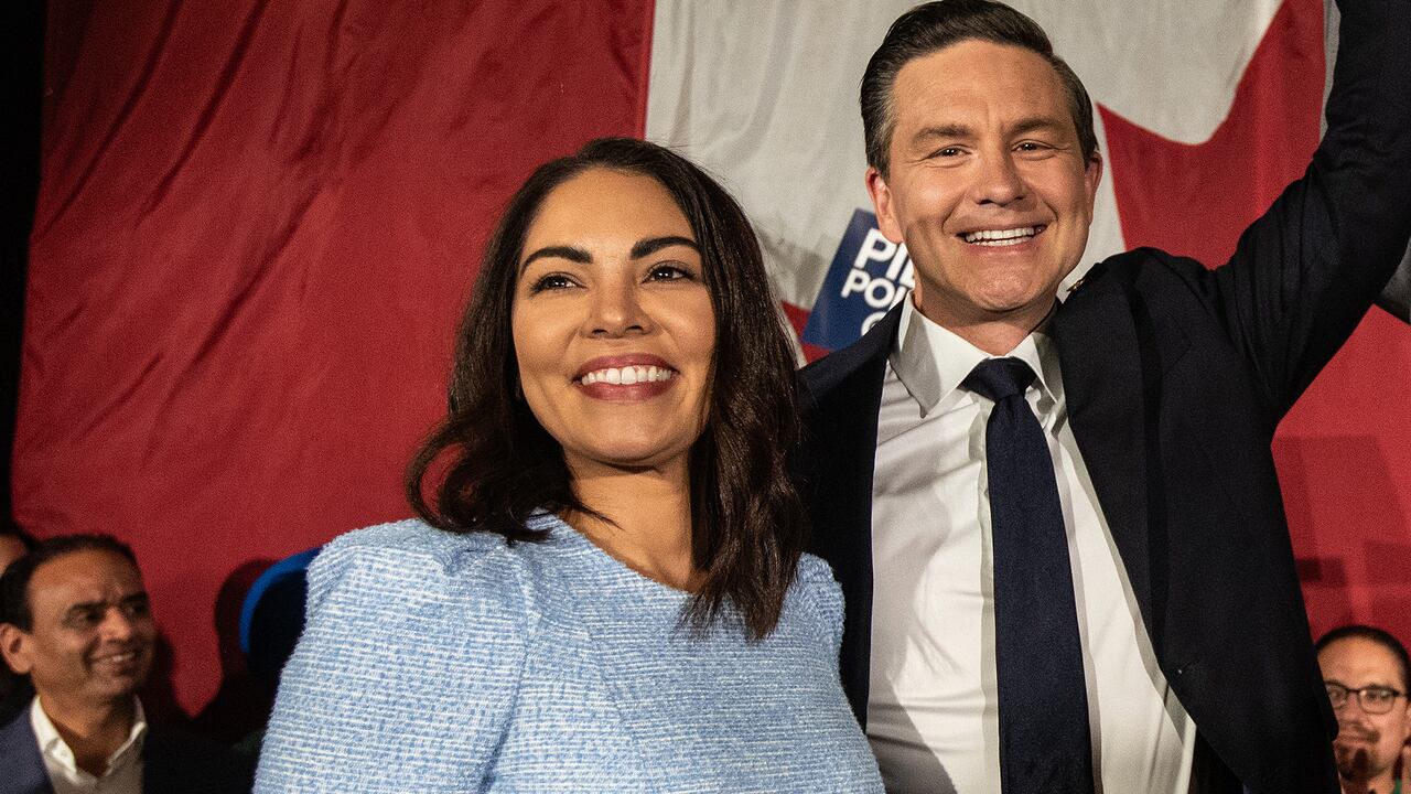 A man and a woman smile on a stage.