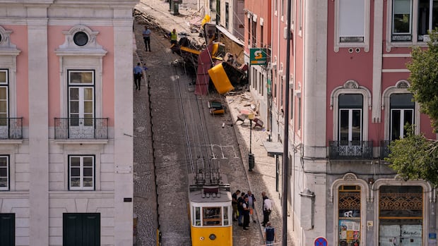 Police officers inspect the site where a tourist streetcar derailed and crashed in Lisbon, Portugal, Thursday, Sept. 4, 2025. (AP Photo/Armando Franca) Police officers inspect a crumpled streetcar on a narrow street.