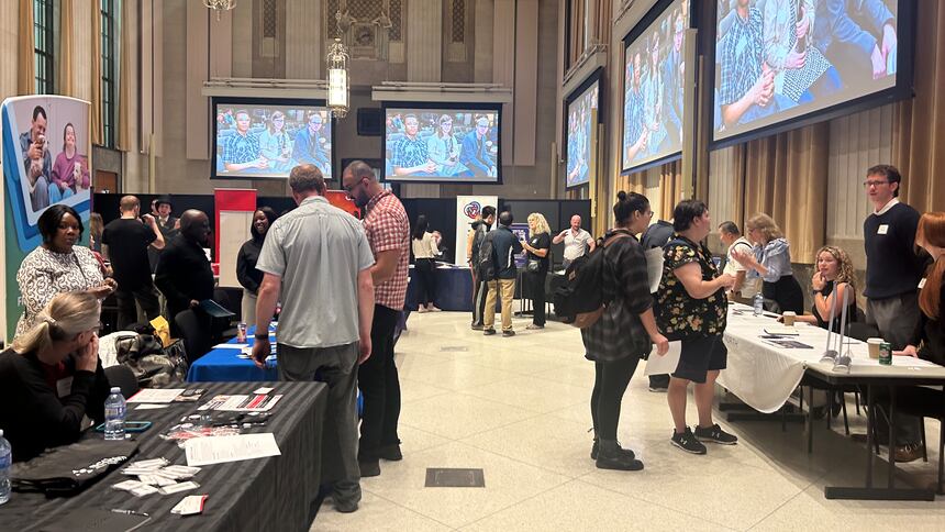 Job seekers stopping by employers' booths at a job fair