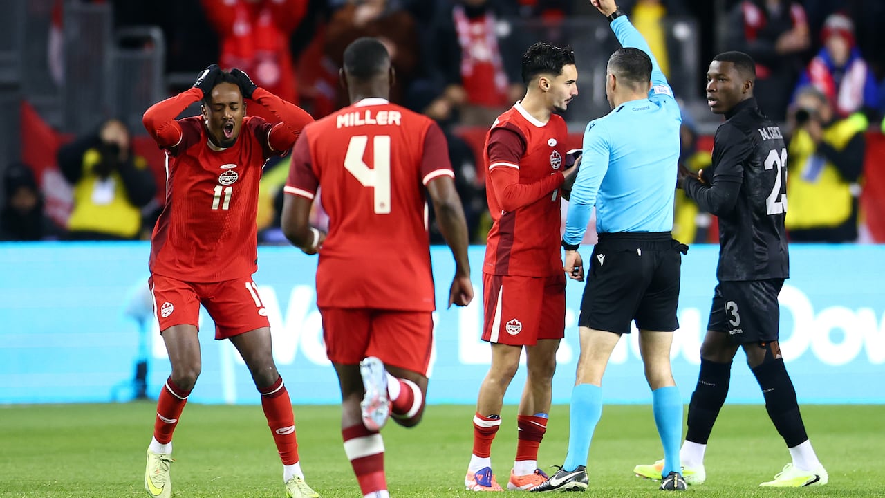 A referee gives a red card to a soccer player.