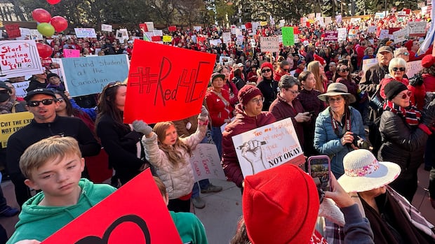 People gather in downtown Calgary on Oct. 5 to show support for teachers as a provincewide strike looms. people at a rally, many wearing red and carrying signs