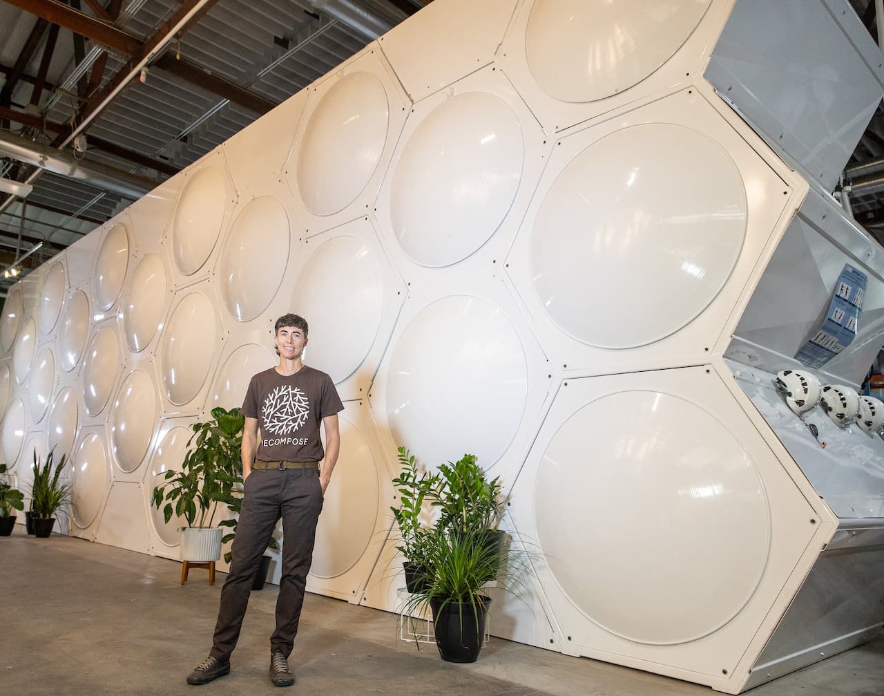 A person in pants stands in front of a beige wall with a honeycomb pattern in it